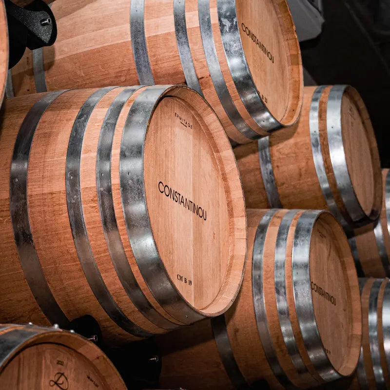 Wooden barrels with 'Constantinou' branding in a storage area.