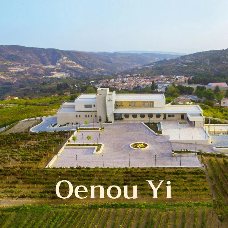 Aerial view of a building with 'Oenou Yi' branding, surrounded by vineyards and hills.