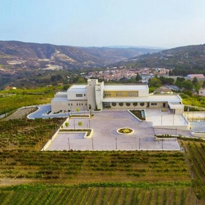 Modern building surrounded by greenery and hills under a clear sky