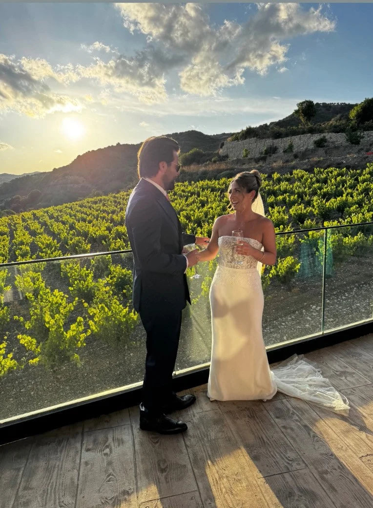 Couple standing on a balcony overlooking vineyards with a scenic background
